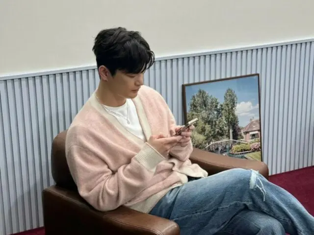 Seo In Guk looks relaxed in a pink cardigan... What is he looking at on his phone?