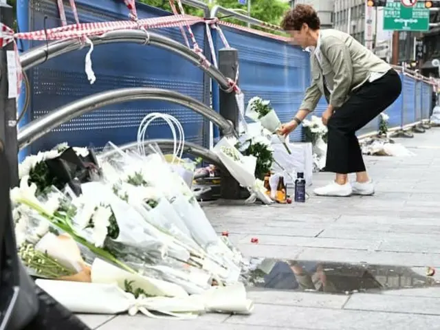 市庁近くの事故現場で、犠牲者を追悼して献花する市民