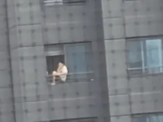 Man smoking while sitting on railing of 20th floor apartment building causes controversy (South Korea)