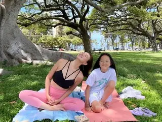 Model SHIHO meditates on the grass in leggings...her daughter Saran is with her