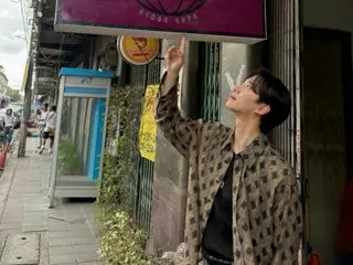 2PM's Lee Junho promotes himself in front of the Thai Taepoong Trading Company sign